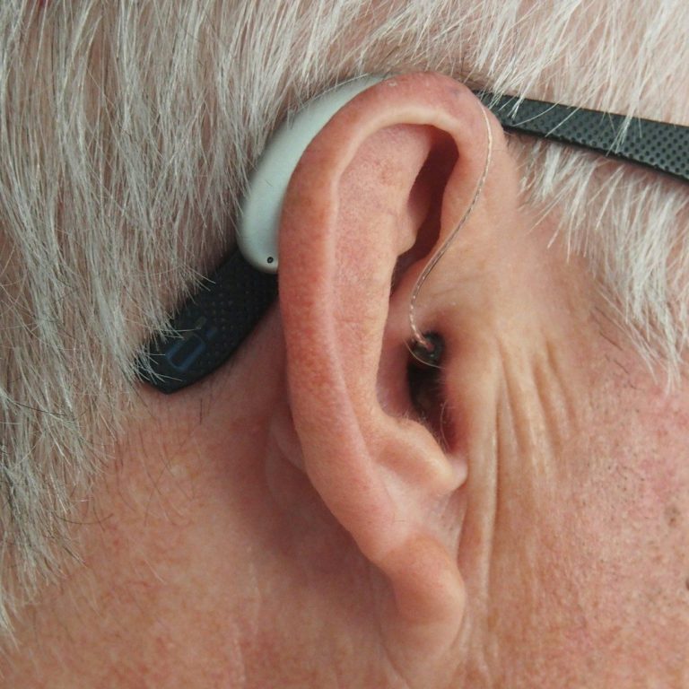 image of an ear of an elderly gentleman wearing a hearing aid. 